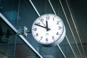 A large white analog clock mounted on the glass wall of a modern building in Osijek, Croatia.